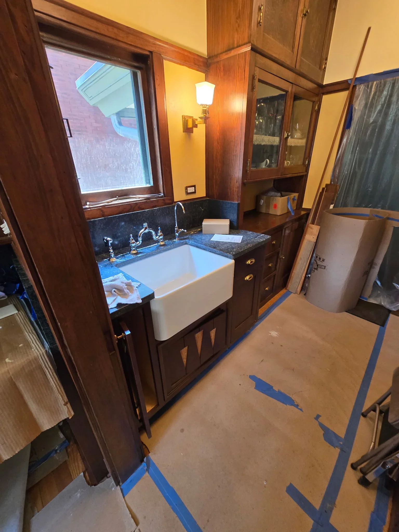White farmhouse sink with chrome faucet installed in dark wood bathroom vanity with granite countertop