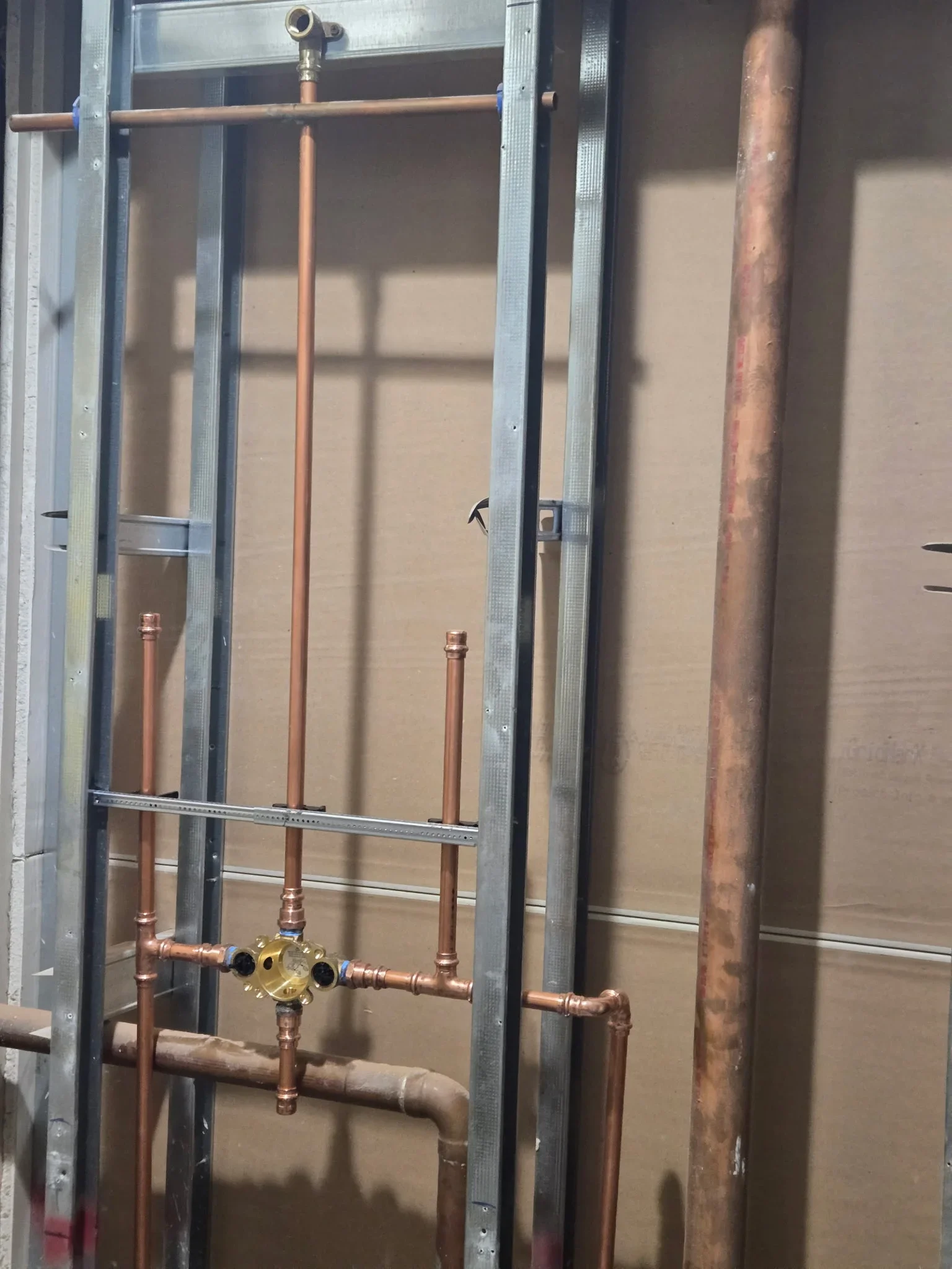 Copper pipes with brass valve assembly and soldered joints installed in metal framing