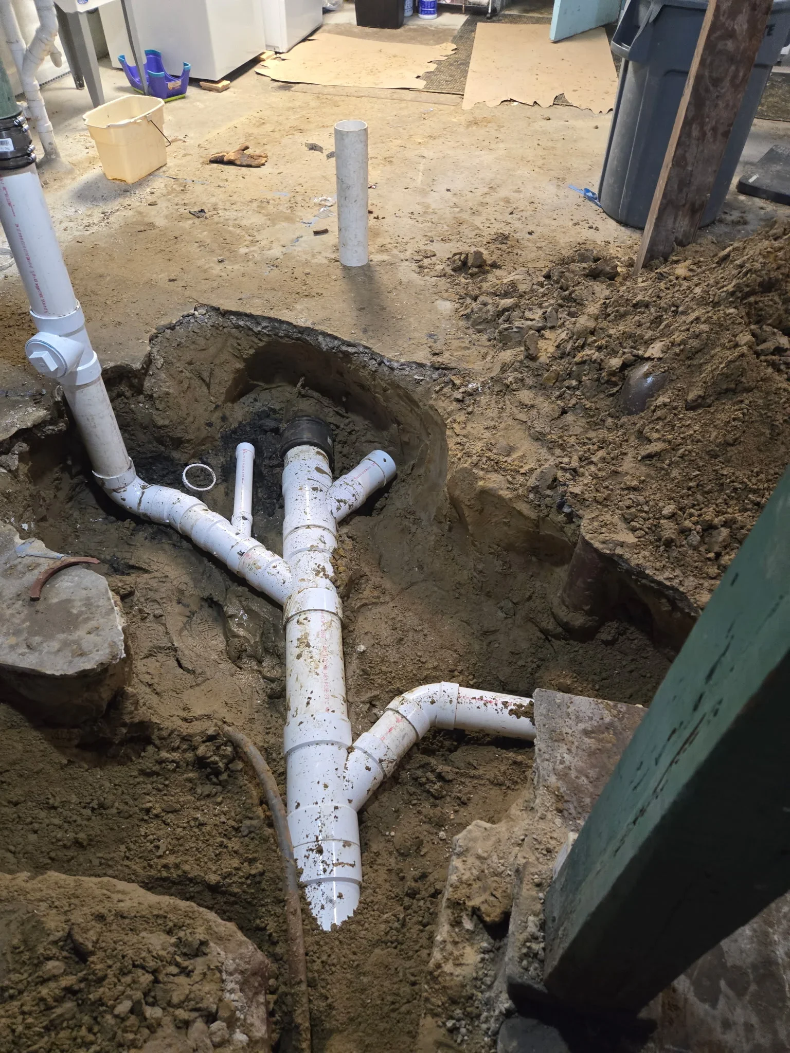 Underground PVC drain pipe installation with multiple branch connections in excavated trench